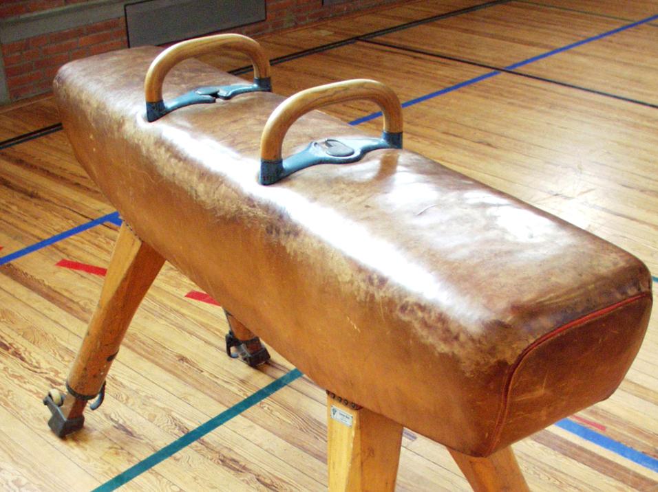 Turnbank mit Holzgriffen auf einem Holzfußboden in einer Sporthalle.